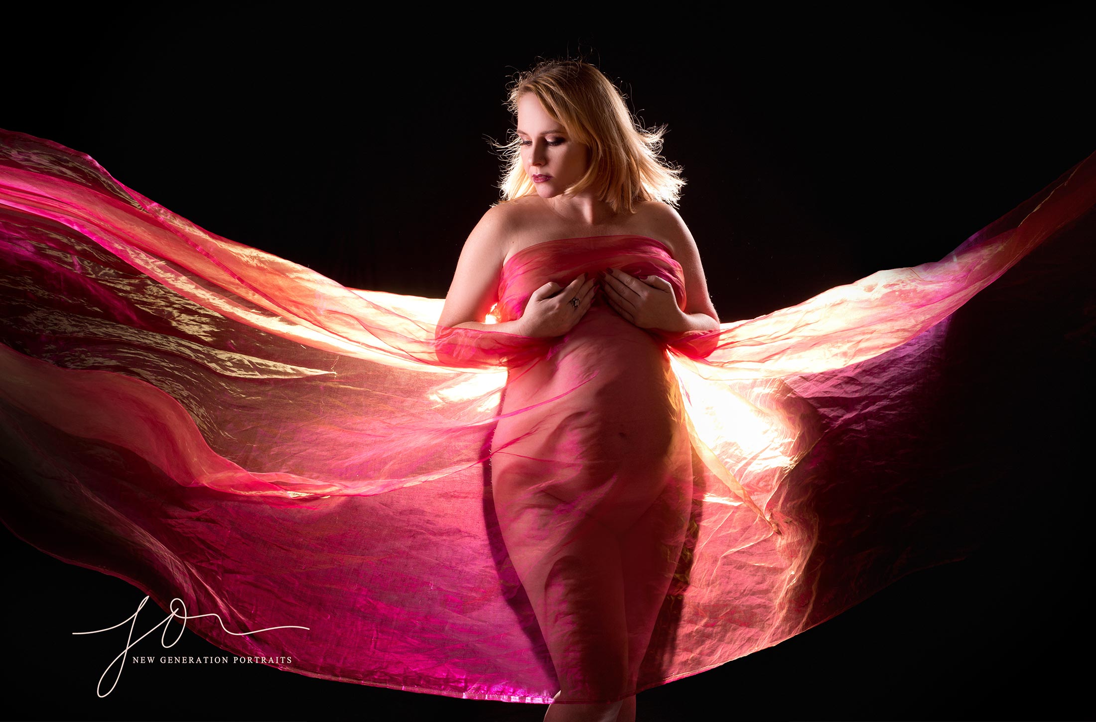 Mum to be covered in red fabric back lit. Pregnancy Boudoir Photography Shoot