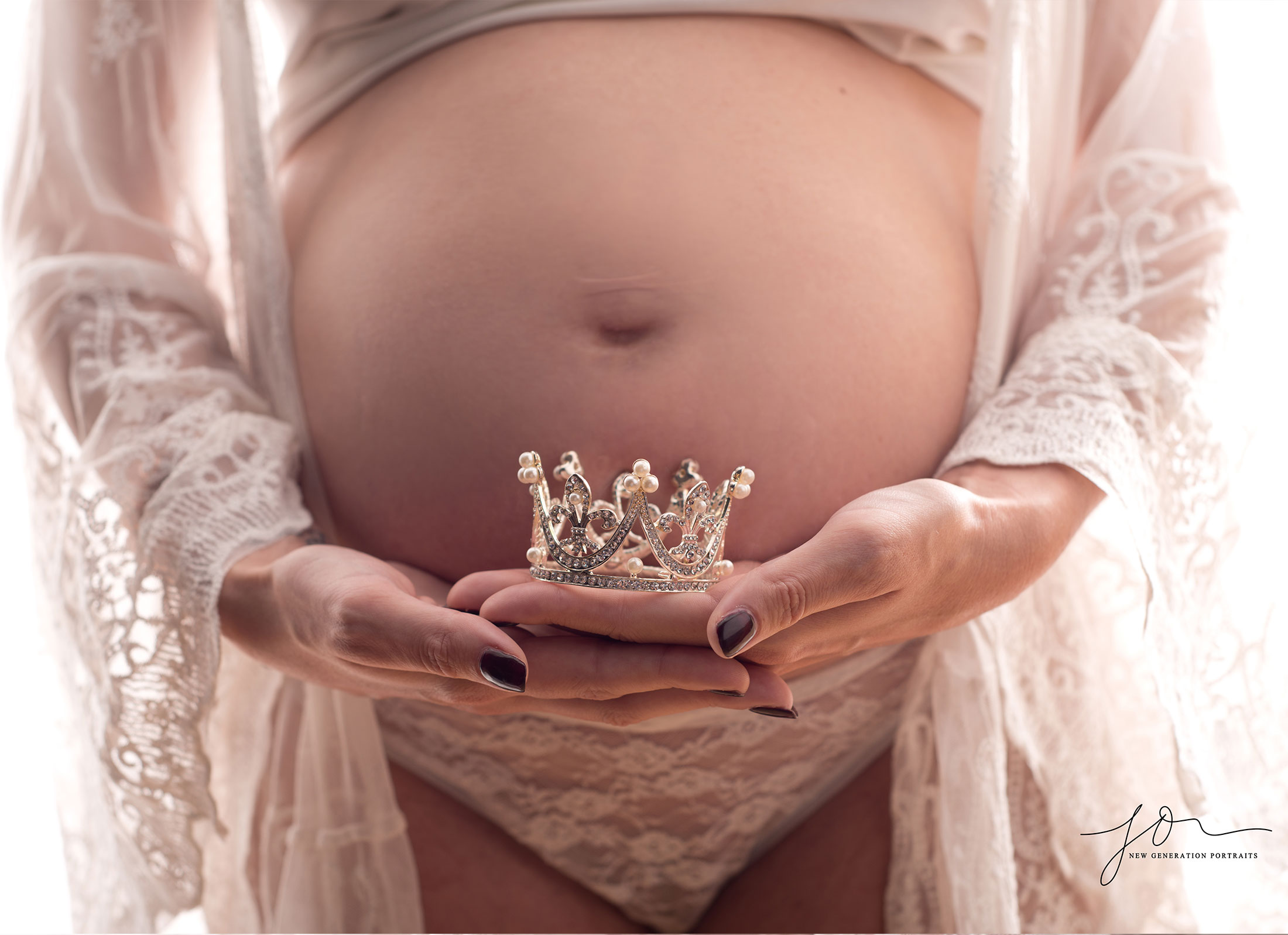 Holding princess or prince crown in front of baby bump. Captured by New Generation Portraits.