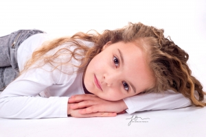 Pretty little girl lay on her tummy for her portrait. Captured by New Generation Portraits, Wirral.
