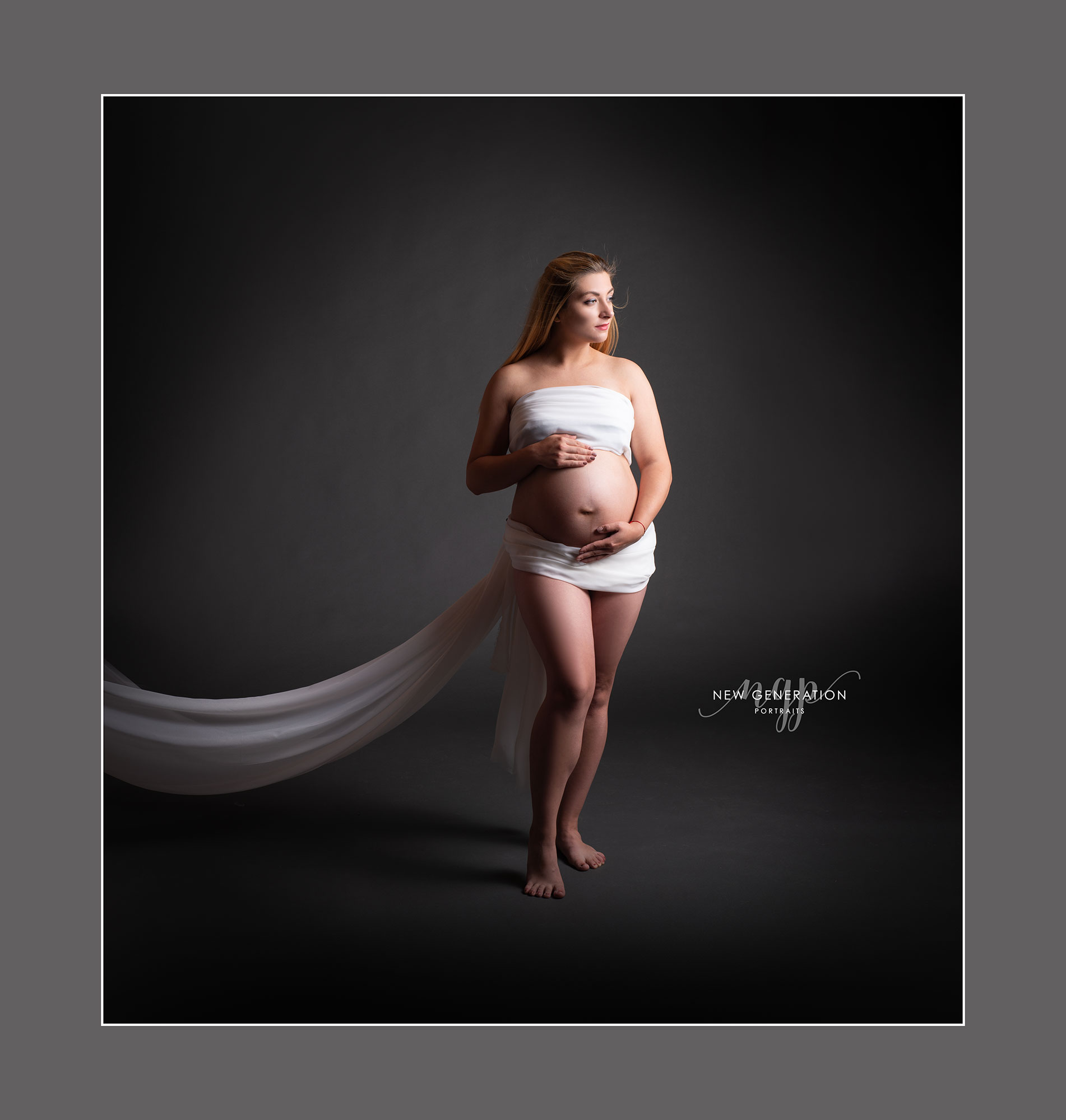 Pregnant lady wrapped white fabric in our wirral professional studio. Captured by New Generation Portraits.