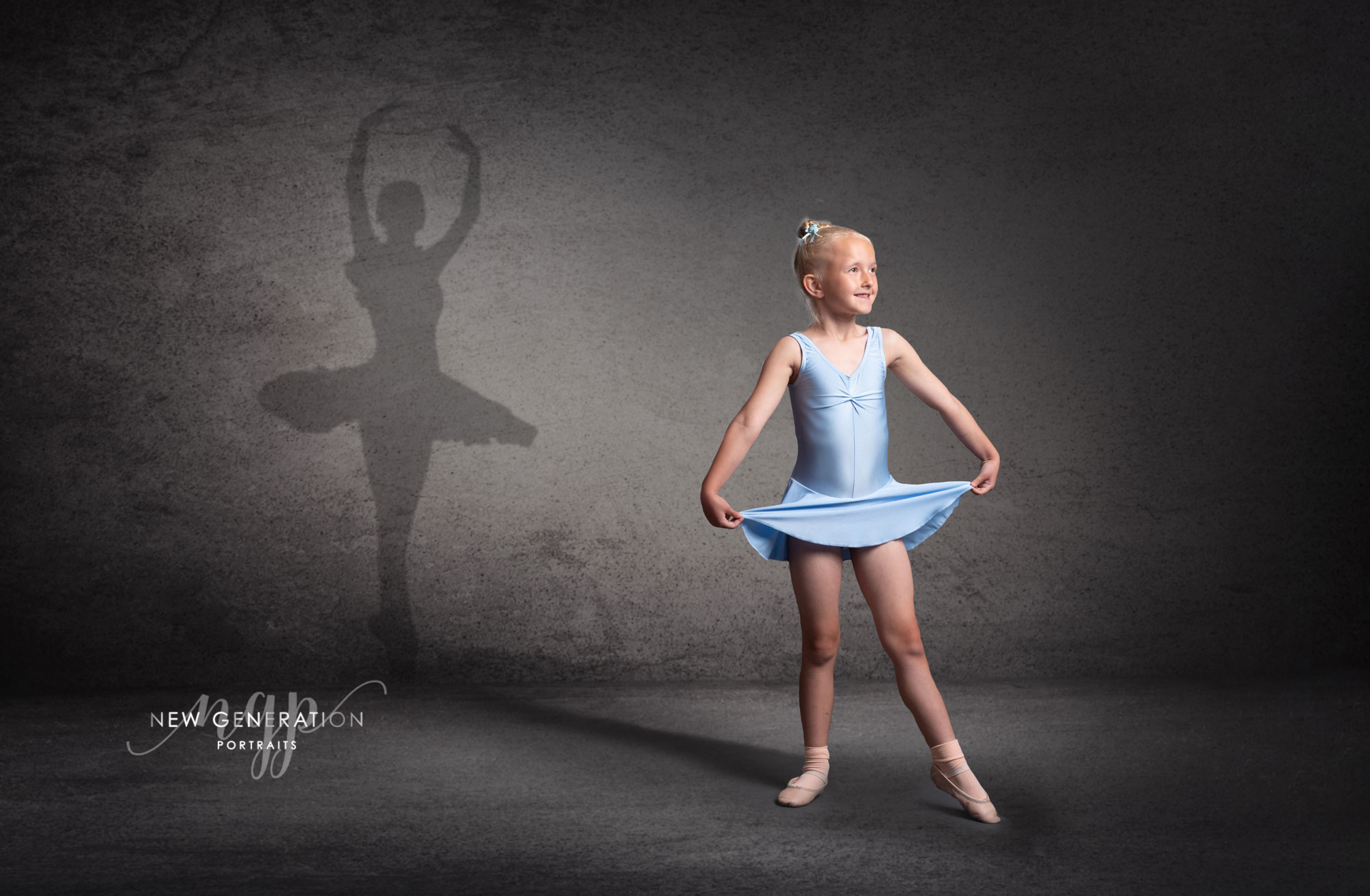 Child Ballet dancer holding a pose with her shadow as a Prima ballerina .