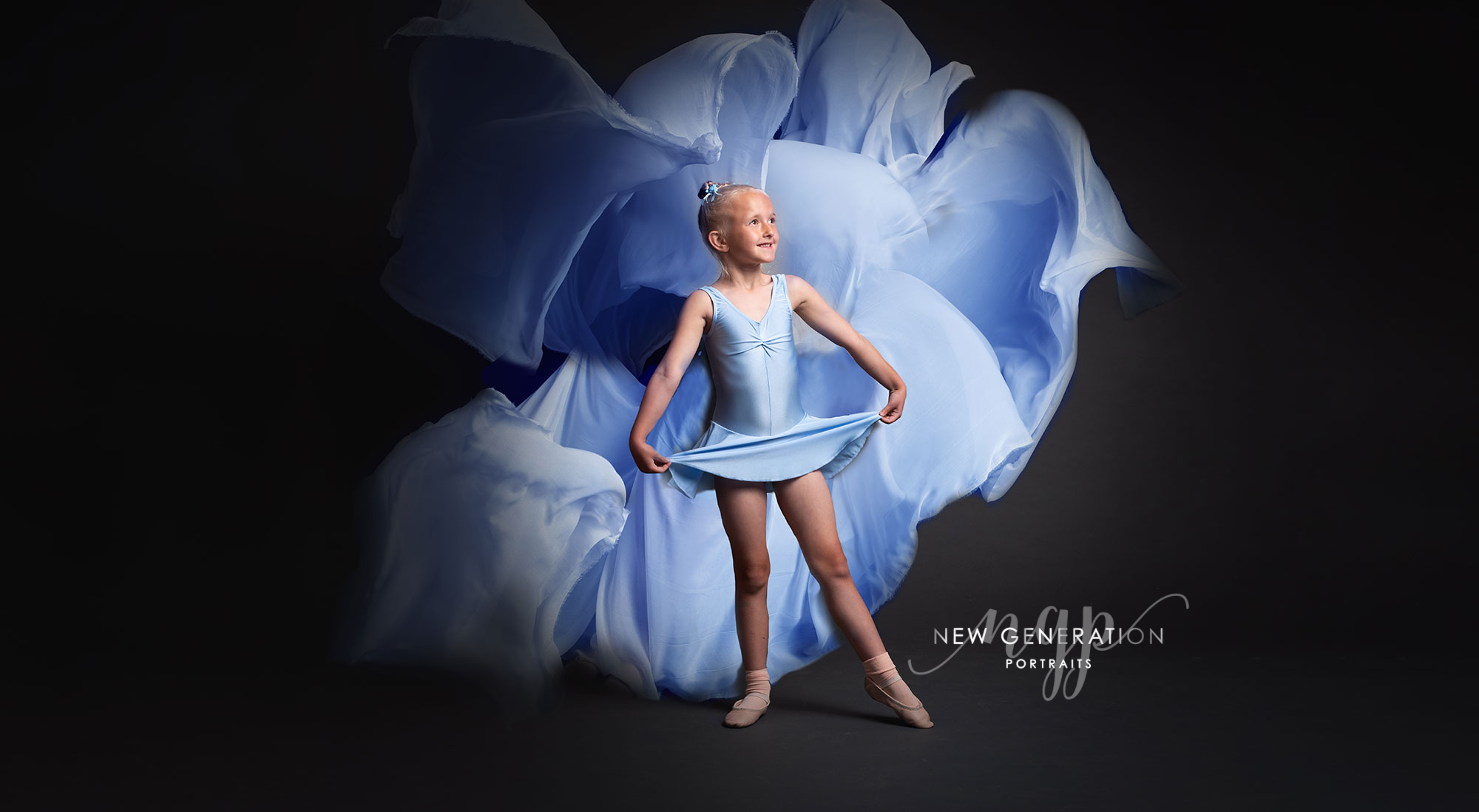 Little ballerina with blue cloud of material being her. Captured by New Generation Portraits