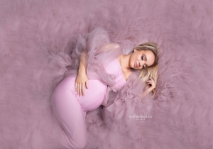 Beautiful mum to be lay on her side in a pink gown captured by New Generation Portraits