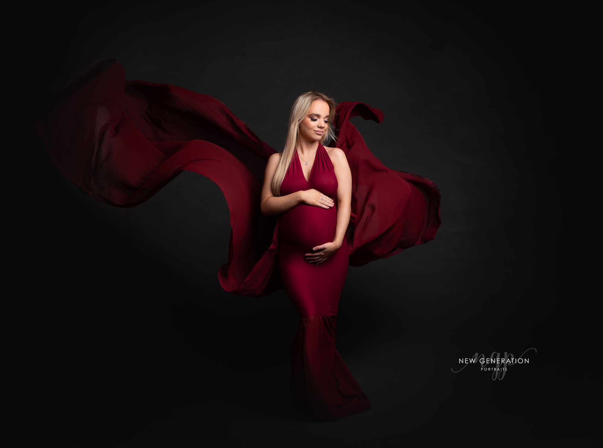 Stunning mum to be in one of our studio gowns. Photographed on a dark background. Captured by New Generation Portraits