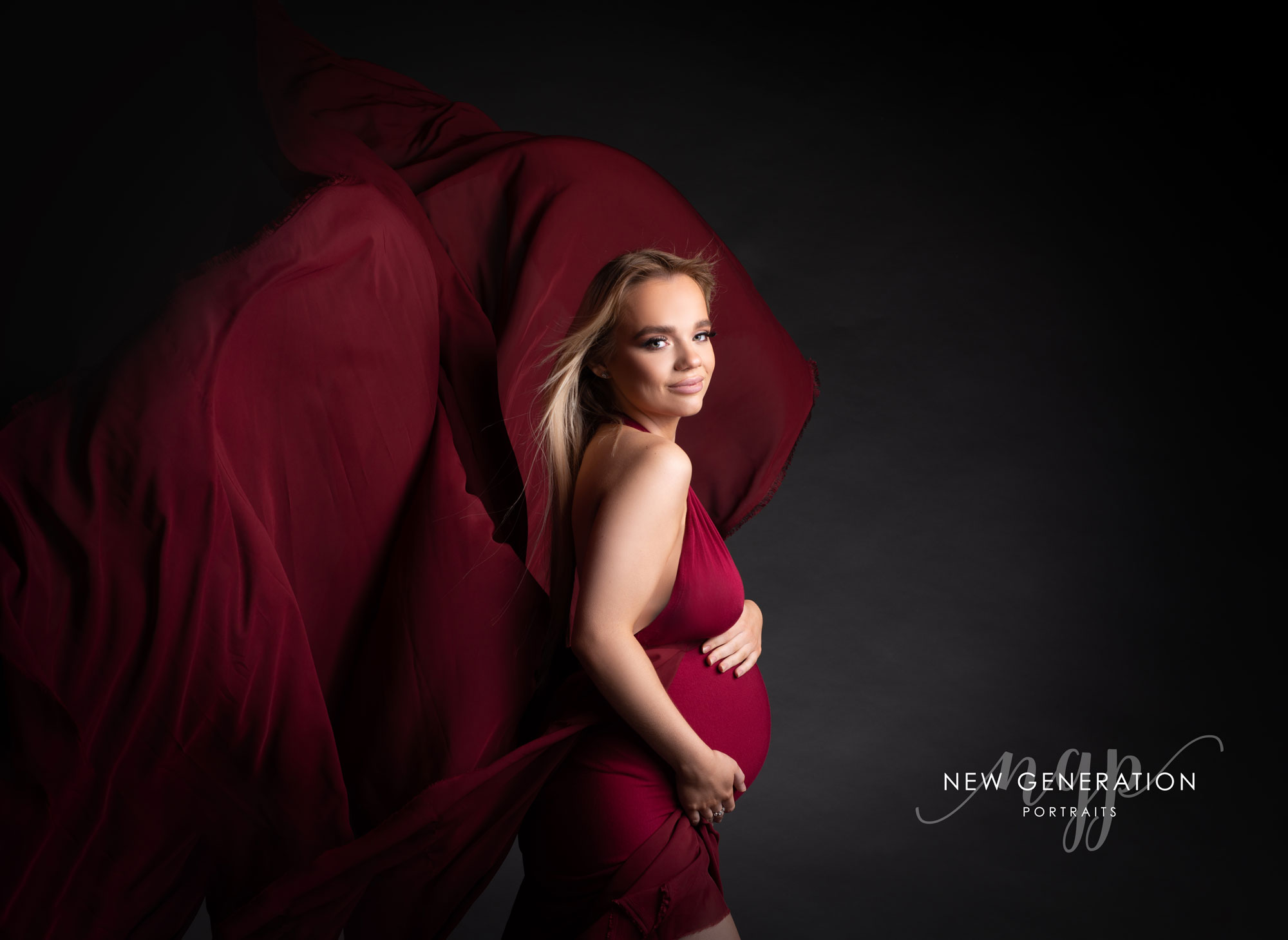 Pregnant lady in claret coloured dress with wind through her hair at New Generation Portraits Ltd