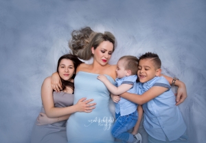 Mum with her three children lay holding each other. Captured by New Generation Portraits