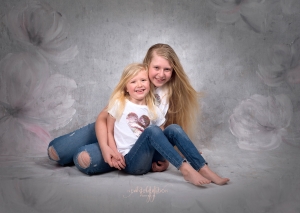 Sisters laughing at the camera in their portrait session. Captured by New Generation Portraits